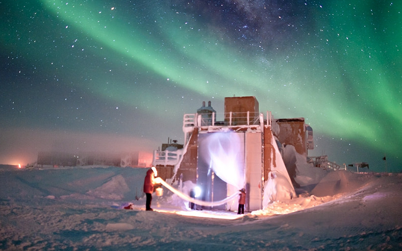 A plastic balloon being launched at the South Pole, with Auroras in the background. Credit: Patrick Cullis, CIRES/NOAA